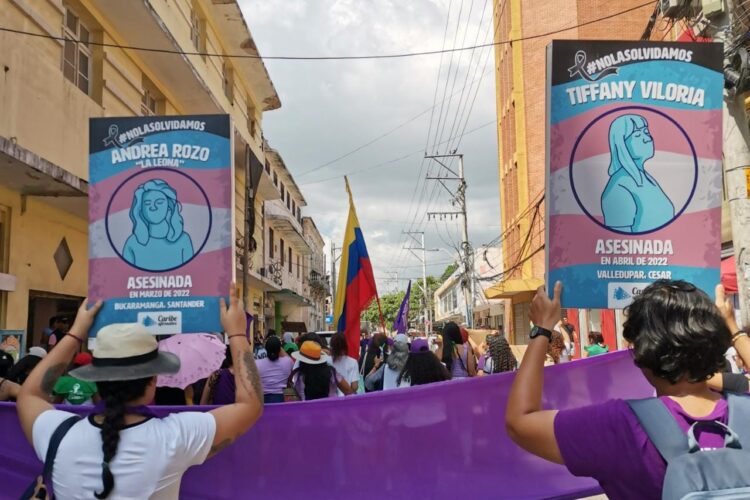 Dos mujeres en una movilización feminista alzan las imágenes de chicas trans asesinadas.