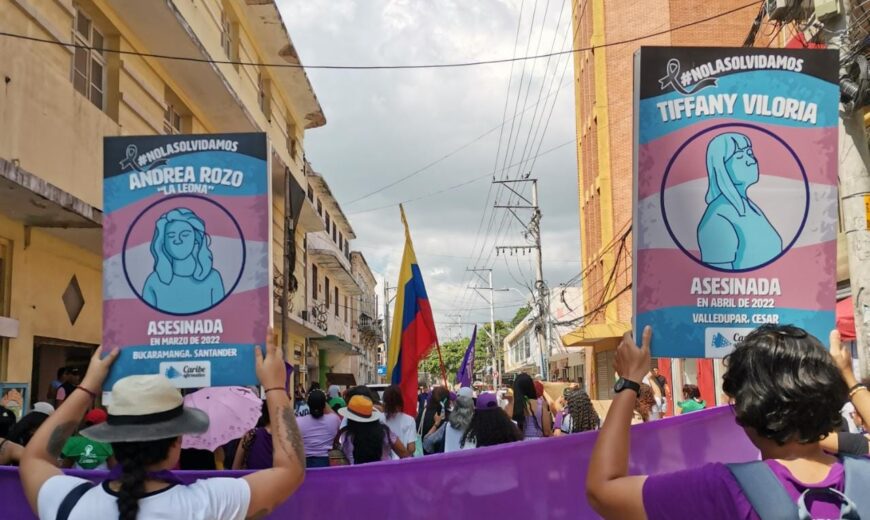 Dos mujeres en una movilización feminista alzan las imágenes de chicas trans asesinadas.