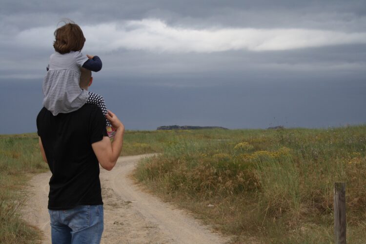 Un padre alza a su hija en hombros.